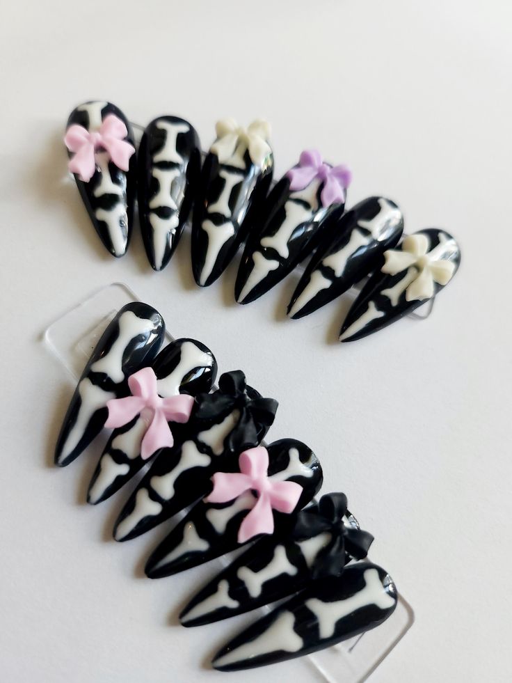 Bold Black and White Bone-Inspired Nail Design with Playful Pastel Bow Accents.