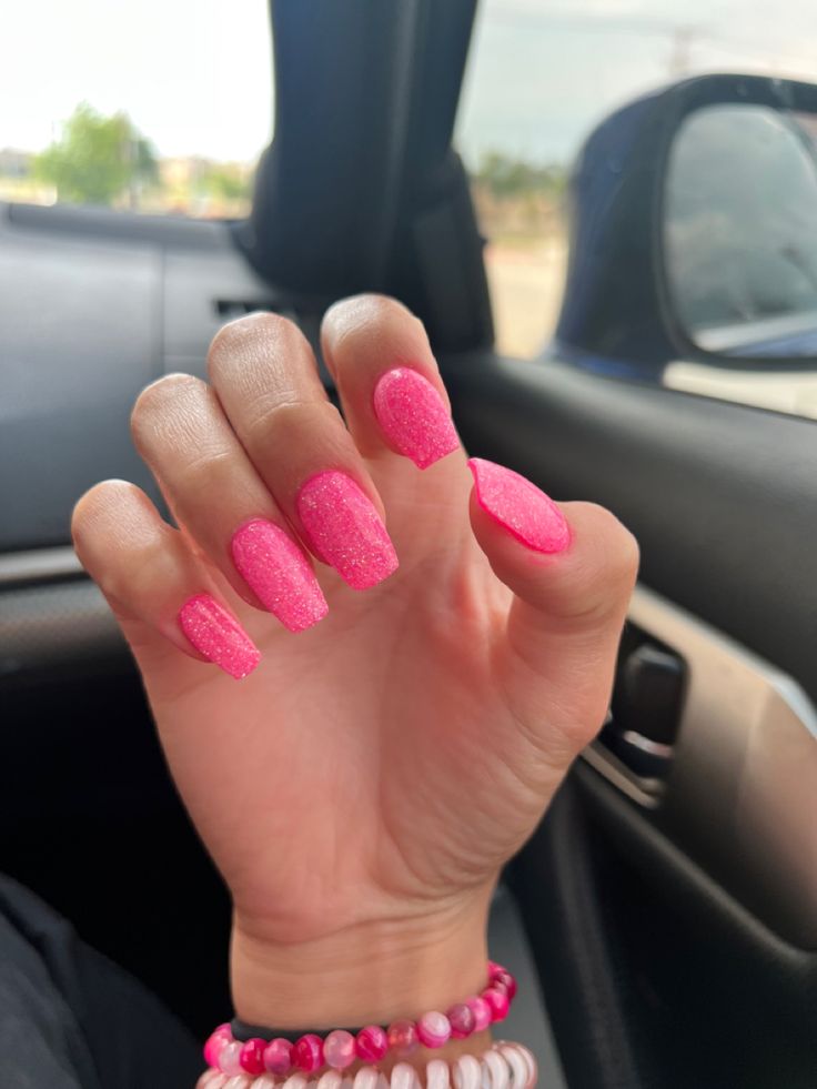 Trendy Sparkling Pink Nails with Elongated Shape and Colorful Accessories for a Bold Statement.