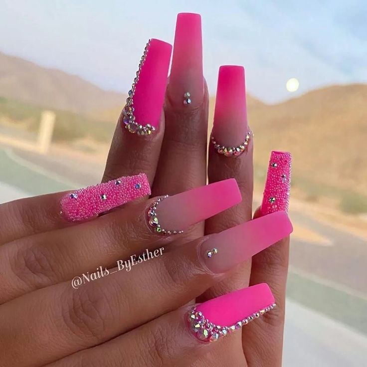 Vibrant Pink Ombre Nail Design with Glamorous Rhinestones and Textures.