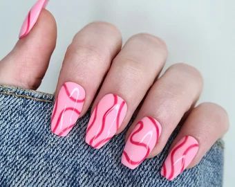 Playful Pink Nail Design with Wavy White Lines for a Trendy Statement Look.