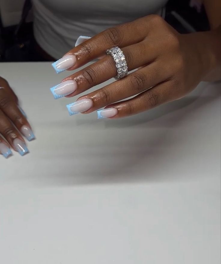 Elegant Ombre Nail Design with Light Blue French Tips and Sparkling Accents.