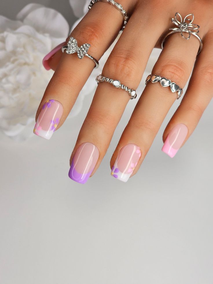 Elegant Gradient Nail Design in Soft Pink and Lavender with Floral Accents and Silver Rings.