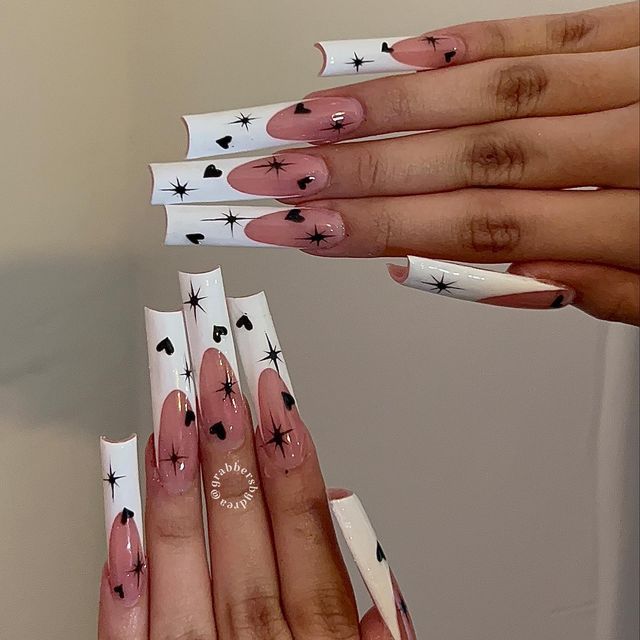 Chic Long Acrylic Nails: Playful Nude and White Design with Black Hearts and Stars.