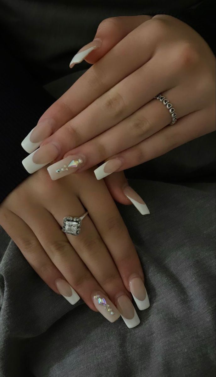 Sophisticated French Tip Manicure Enhanced with Sparkling Embellishments and Stylish Rings.