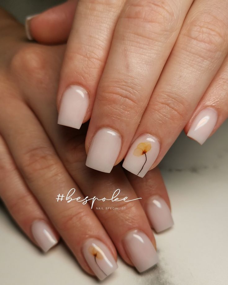 Elegant Nude Nail Design with Glossy Finish and Delicate Floral Accents.