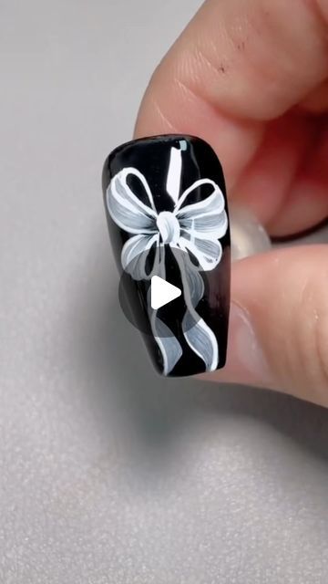 Sophisticated Nail Design: Elegant Black Base with Delicate White Bow Accent