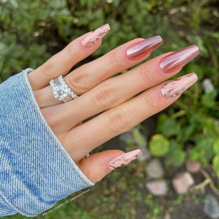 Elegant Metallic Rose Gold Gradient Nails with Marble Effect and Sparkling Accents.