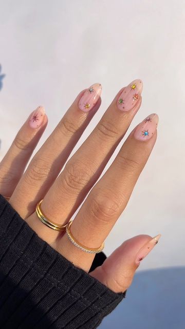 Elegant Nude Nail Design with Colorful Star Accents for a Trendy Look.