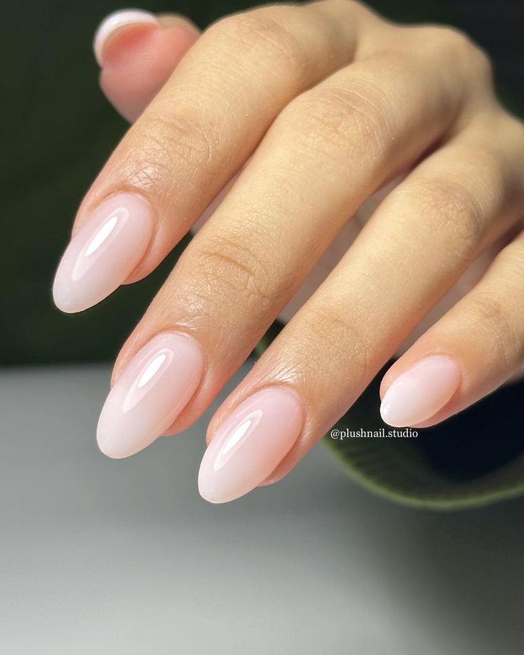 Elegant Almond-Shaped Ombre Nails: A Subtle Blend of Soft Pink and Sheer Nude.