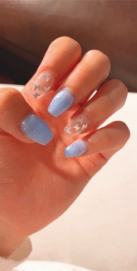 Whimsical Soft Blue Nail Design with Butterfly Motifs and Sparkling Finishes