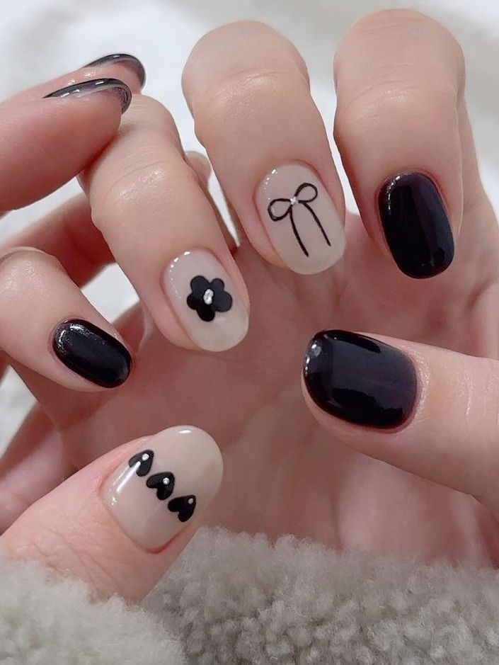 Sophisticated Nail Design Blending Dark and Neutral Tones with Artistic Accents.