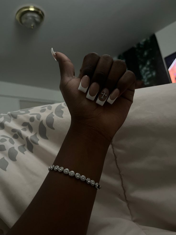 Sophisticated Nail Design: Classic French Manicure with Unique Accent and Delicate Bracelet.