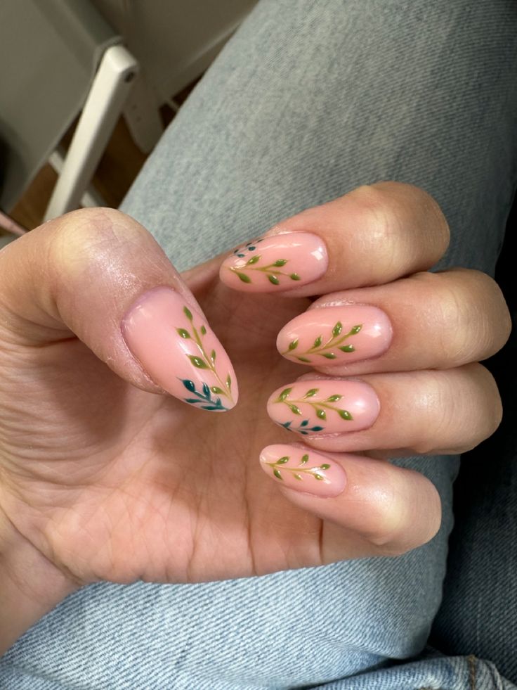 Elegant Nude Nail Design with Delicate Leaf Patterns in Green and Blue.