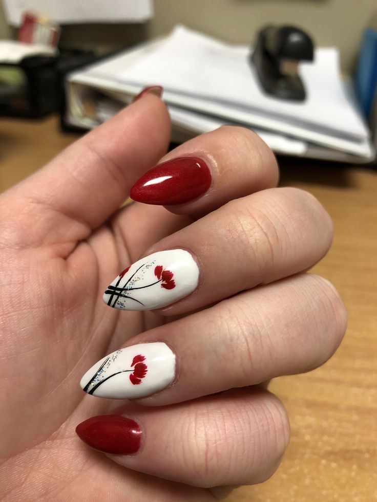 Chic Nail Design: Bold Red and Elegant White with Floral Accents on Pointed Nails.