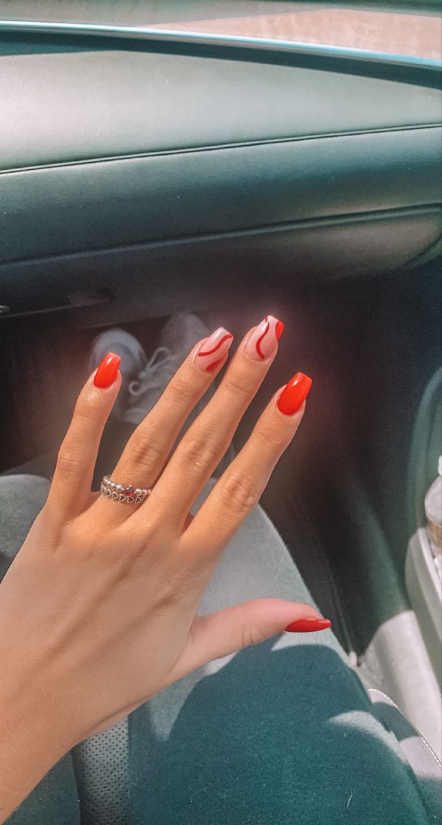 Bold Red Nail Design with Playful White Swirl Pattern for a Striking Statement Look.