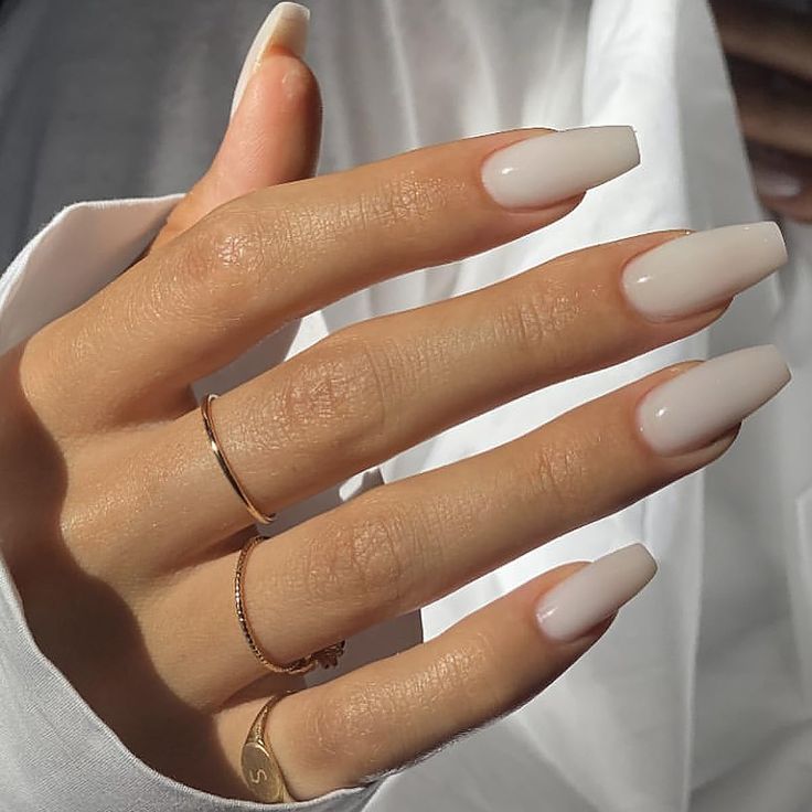 Sophisticated Elegant Almond-Shaped Nails with Muted Nude Polish and Minimalist Jewelry.