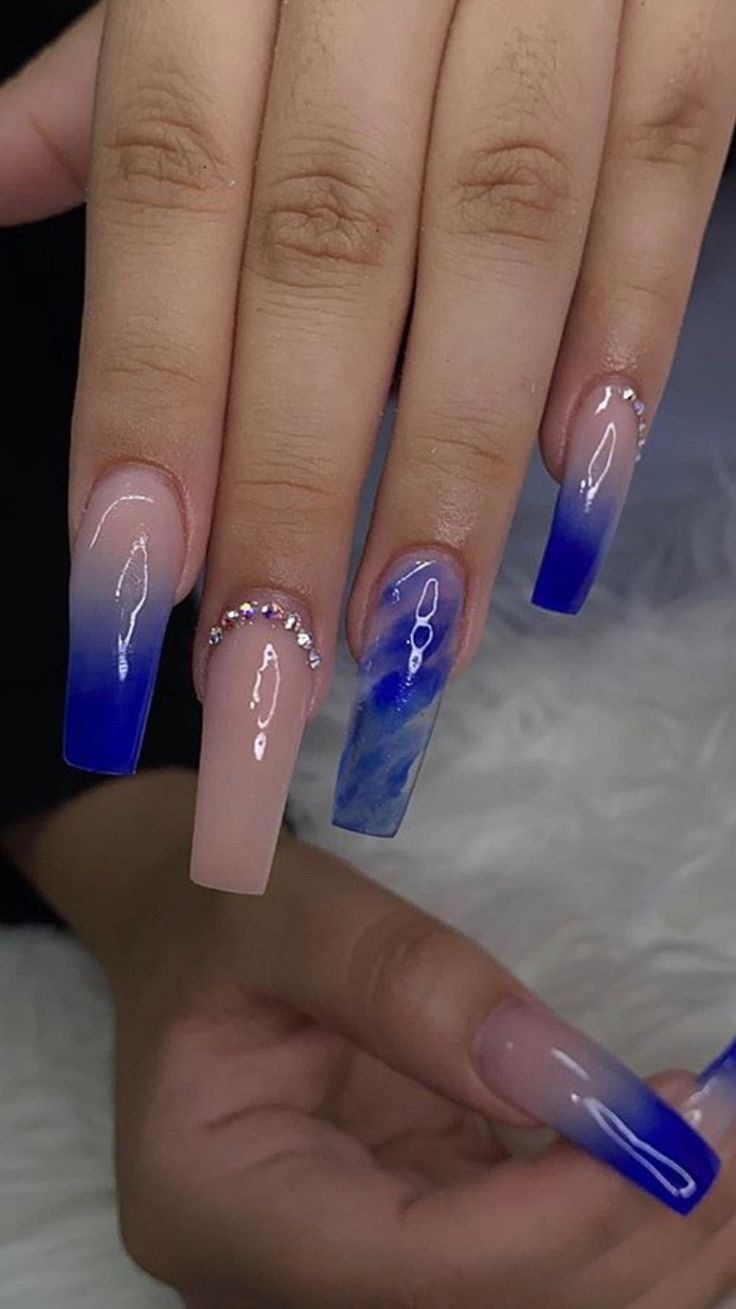 Elegant Ombre Nail Design: Soft Nude to Deep Blue Gradient with Marble Effect and Crystal Accents.