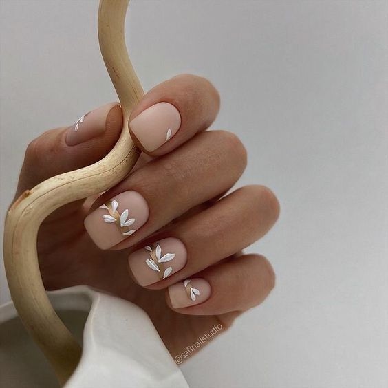 Sophisticated Matte Nude Nail Design with Delicate White Leaf Accents.