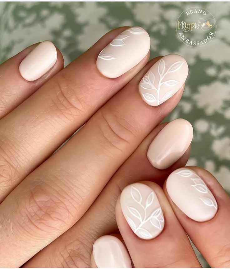 Sophisticated Nude Nail Design with Delicate White Leaf Patterns.