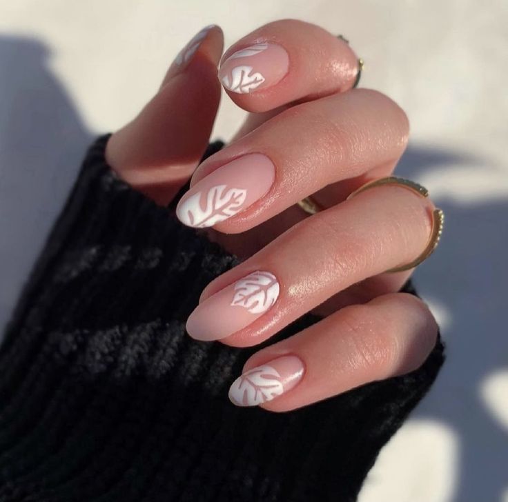 Chic Nude Nail Design with Delicate White Leaf Patterns and Elegant Matte Finish.