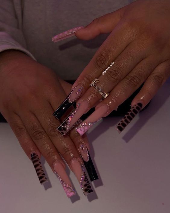 Sophisticated Stiletto Nail Design in Pink and Black with Intricate Art and Sparkly Accents.