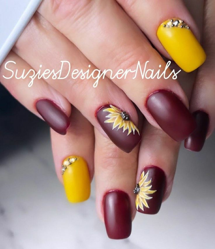 Chic Nail Art: Deep Burgundy and Vibrant Yellow with Sunflower Motifs and Shimmering Rhinestones