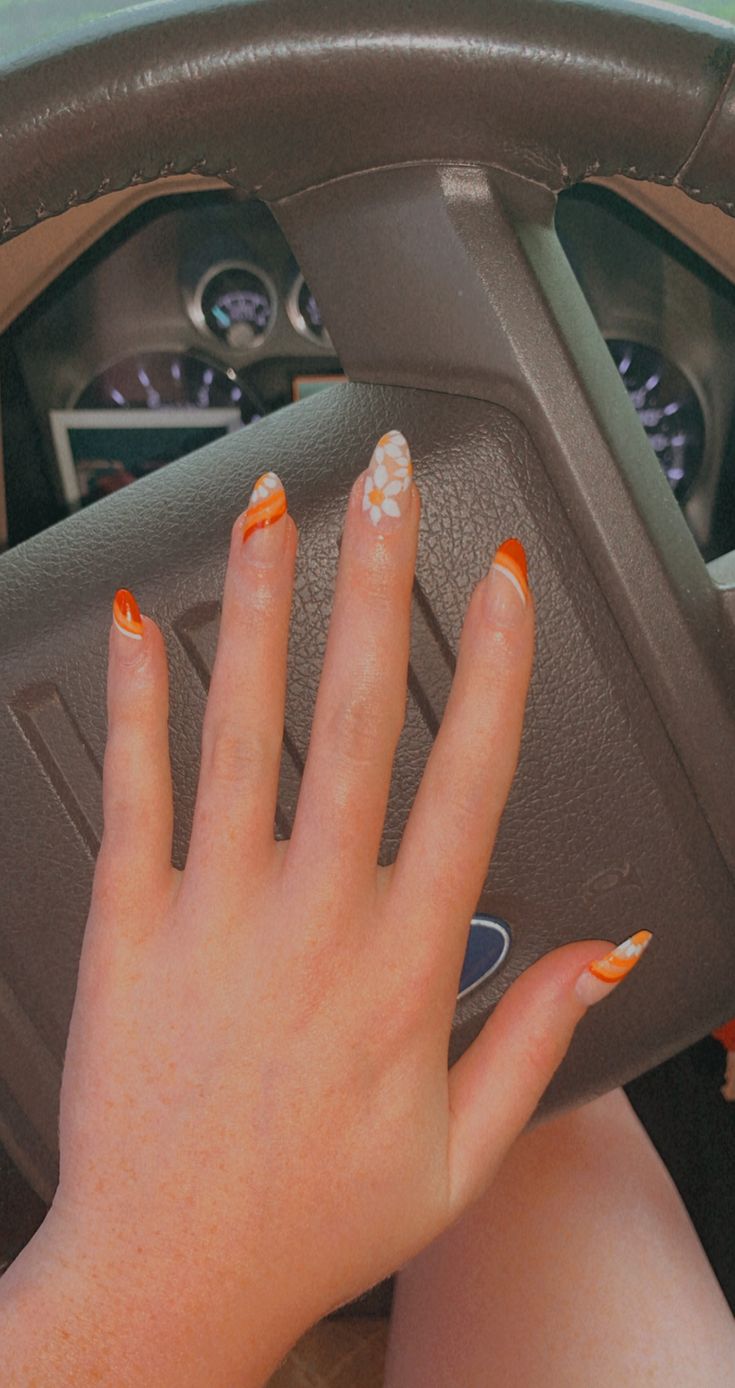 Chic Summer Nail Design: Vibrant Orange Accents and Intricate Floral Patterns.