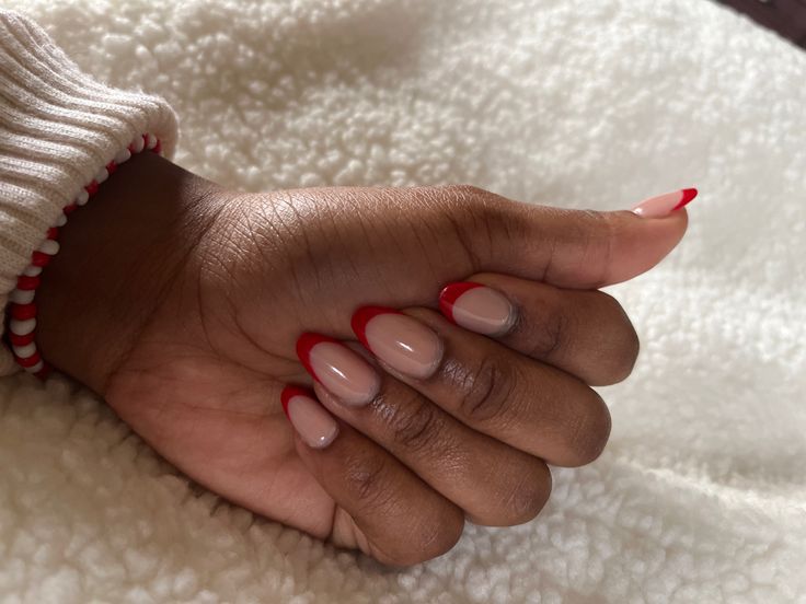 Chic French Tip Manicure: Bold Red Tips on Elegant Nude Base.