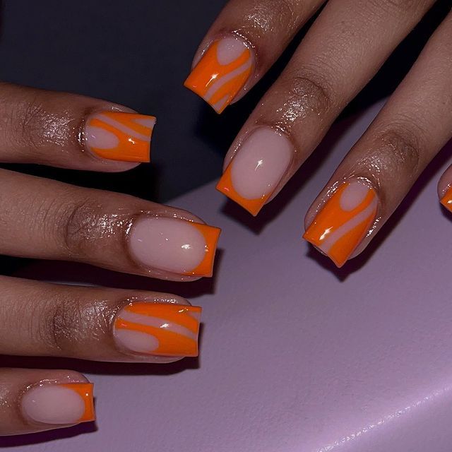 Striking Vibrant Orange and Nude Nail Design with Modern Swirl Pattern and Stylish Finish.