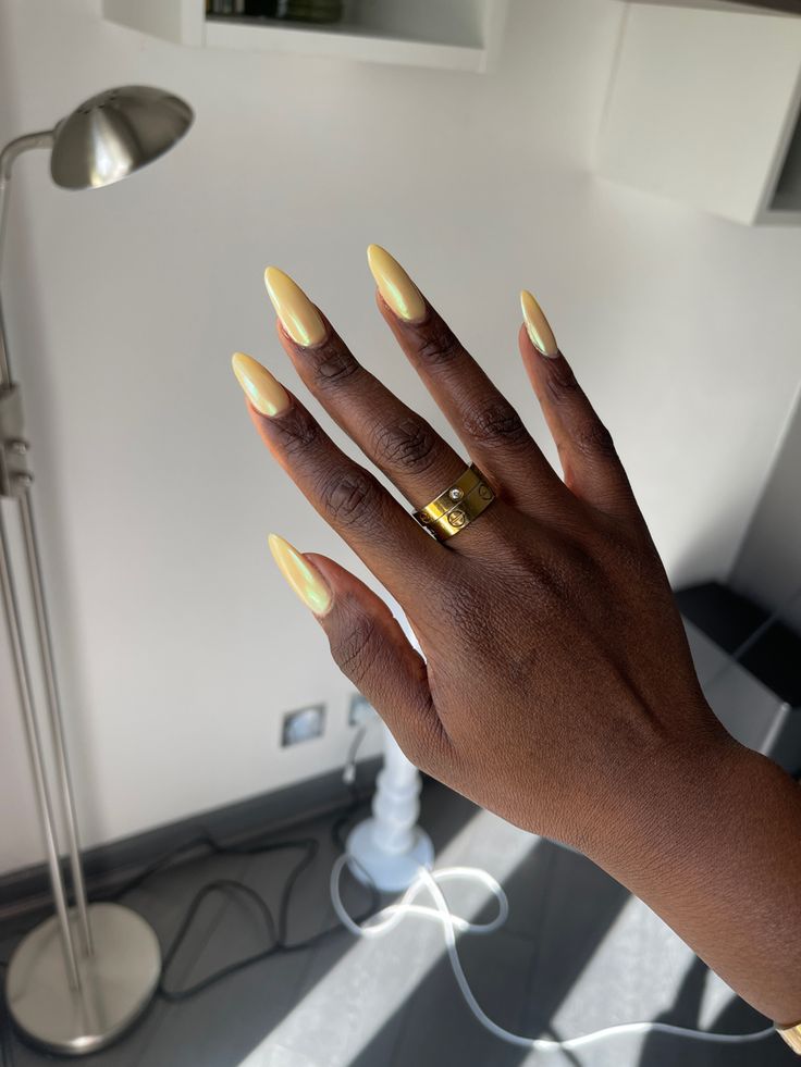 Chic Pastel Yellow Almond Nails with Glossy Finish and Bold Gold Ring for Sophisticated Style.