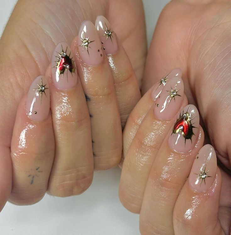 Sophisticated Nail Design: Translucent Nude Base with Red Hearts and Gold Starburst Accents