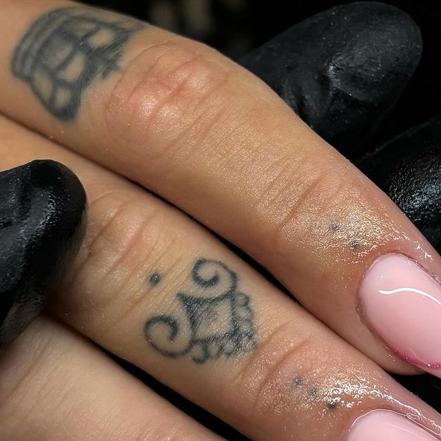 Elegant Pink Nail Design with Glossy Finish and Intricate Black Tattoos for a Unique Contrast.