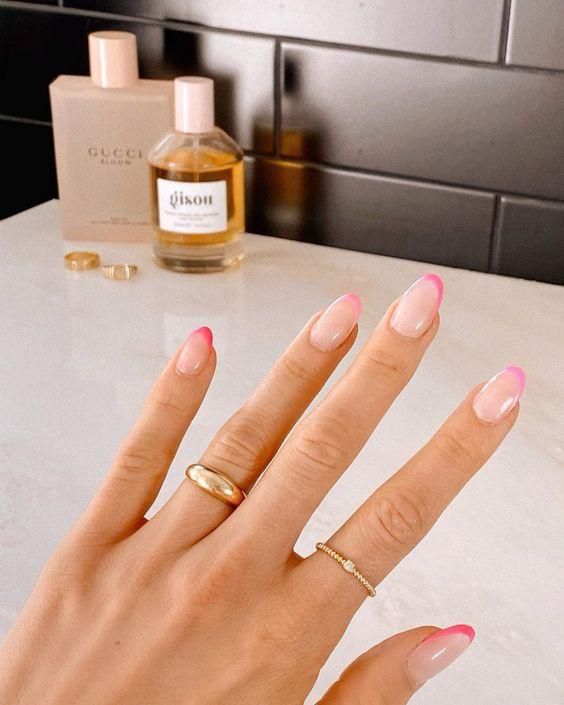 Modern French Manicure: Soft Pink Gradient Almond Nails Accented by Minimalist Rings and Elegant Perfume Bottles.