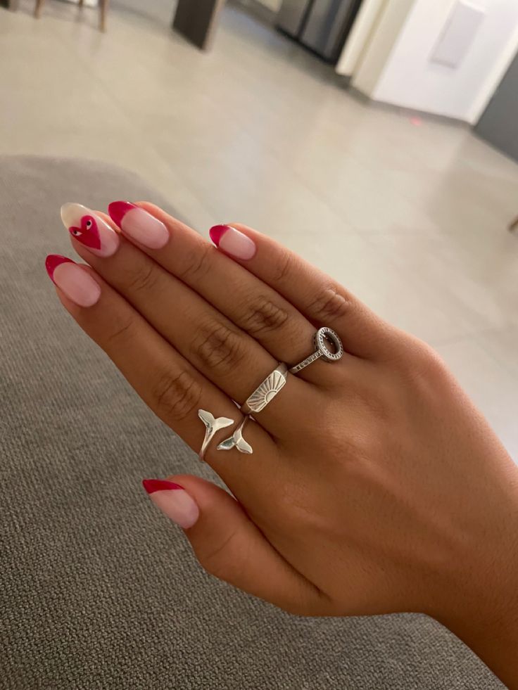 Chic French Manicure with Bold Red Tips and Elegant Silver Rings