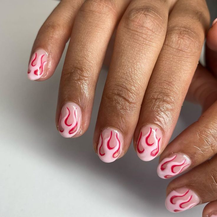 Bold Flame-Inspired Nail Design: Soft Pink Base with Intricate Red Patterns.