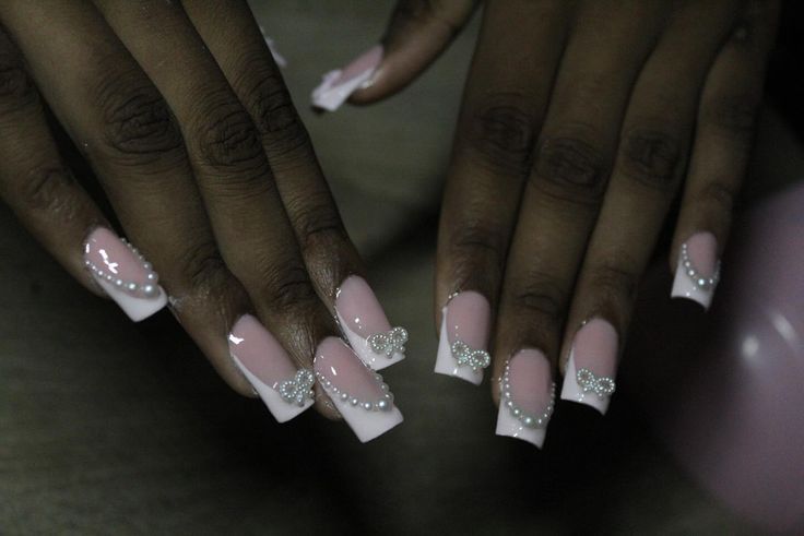 Sophisticated Soft Pink French Tip Nails Embellished with Rhinestone Bows and Pearls.