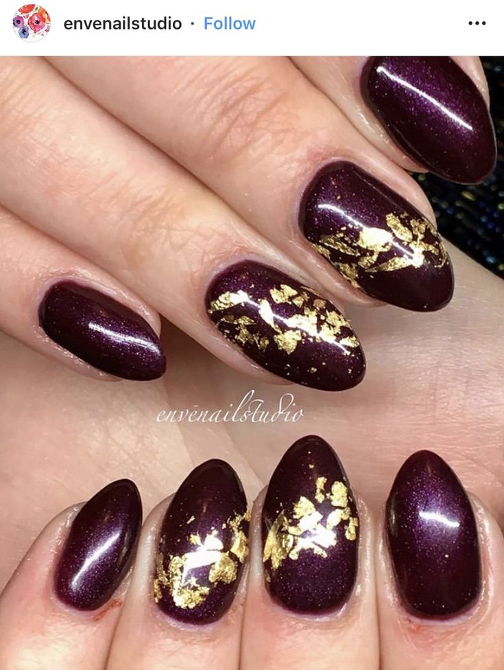 Sophisticated Burgundy Nail Design with Shimmering Highlights and Gold Leaf Accents.