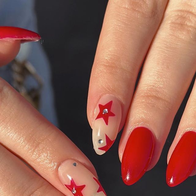 Playful Vibrant Red Nail Design with Star Accents and Glam Rhinestones.