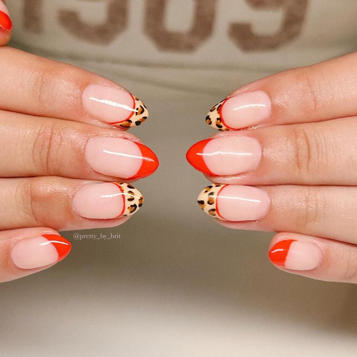 Vibrant Orange Tips and Chic Animal Print Accents Elevate Nail Art Elegance.