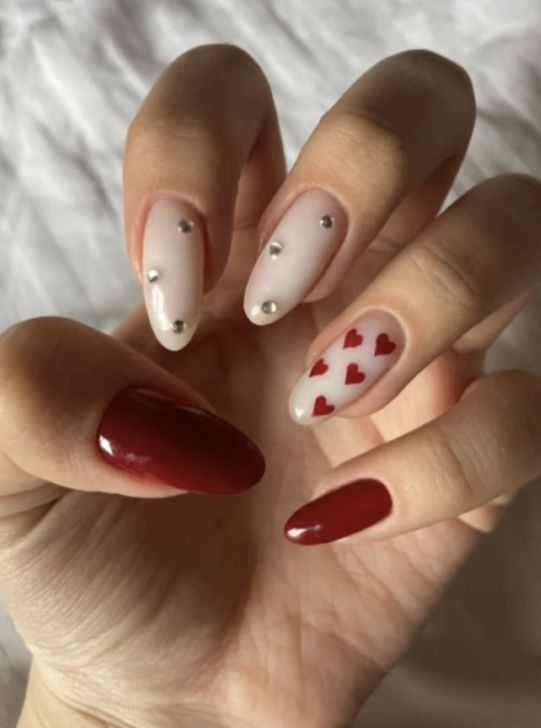 Elegant Red and Nude Nail Design with Playful Hearts and Silver Studs