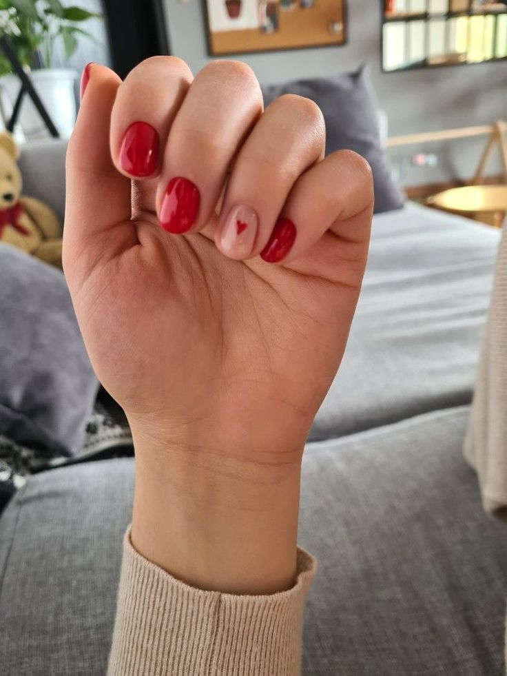 Chic Red and Nude Nail Design with Playful Heart Accent