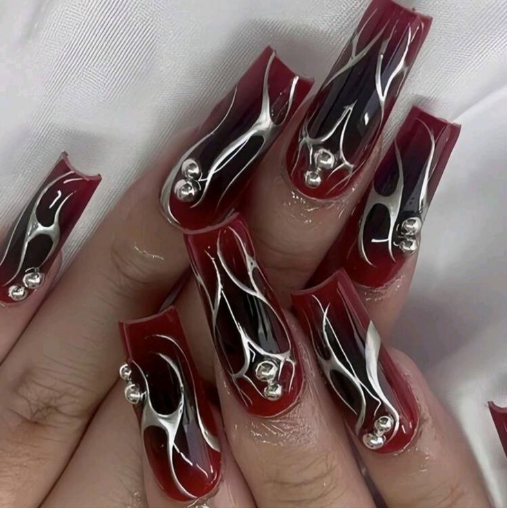 Glamorous Bold Nail Design: Deep Red and Glossy Black with Intricate Patterns and Sparkling Accents.