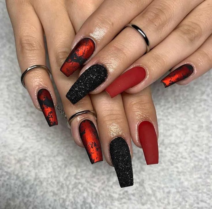 Dramatic Red and Black Nail Design with Matte Finish and Glitter Accents.