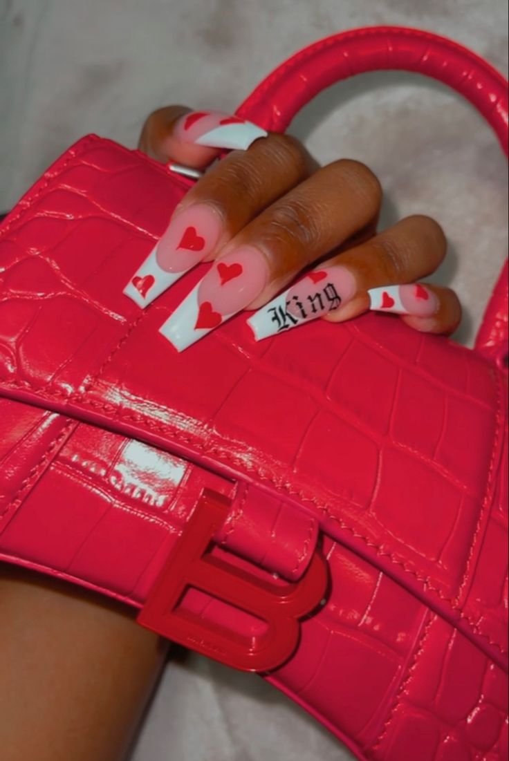 Chic Elongated Nails with Playful Red Heart Design Perfectly Complement a Vibrant Pink Handbag.