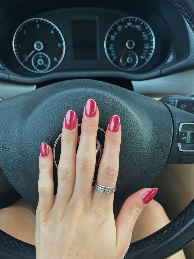 Chic Almond-Shaped Red Manicure with Glossy Finish and Metallic Accents.