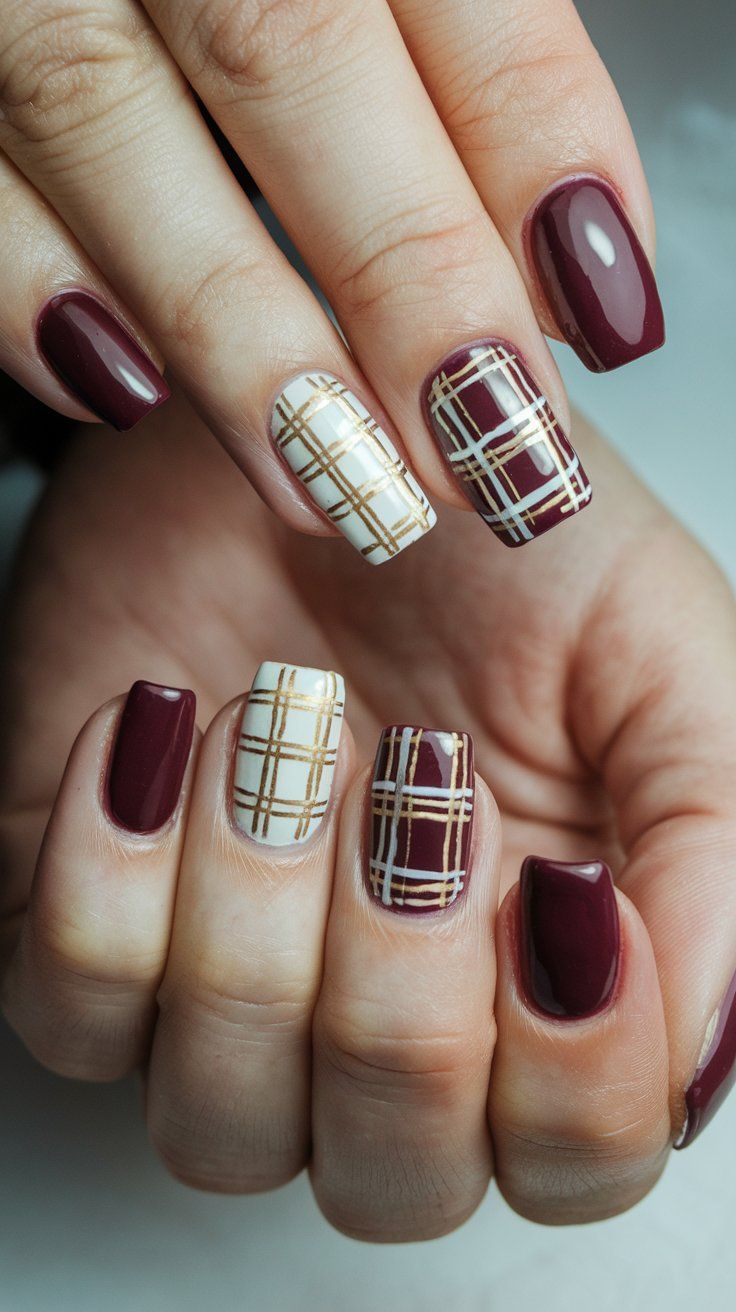 Sophisticated burgundy and plaid nail design with contrasting finishes and gold detailing.