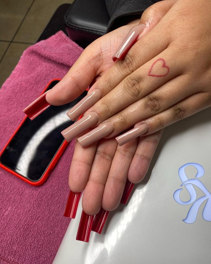 Chic Nail Design: Nude and Deep Red Contrast with Bold Elongated Shape.