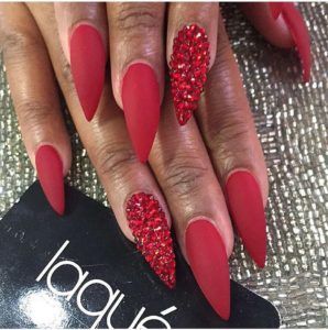 Matte Red Stiletto Nails with Accent Rhinestones: A Bold and Luxurious Look for Any Occasion.