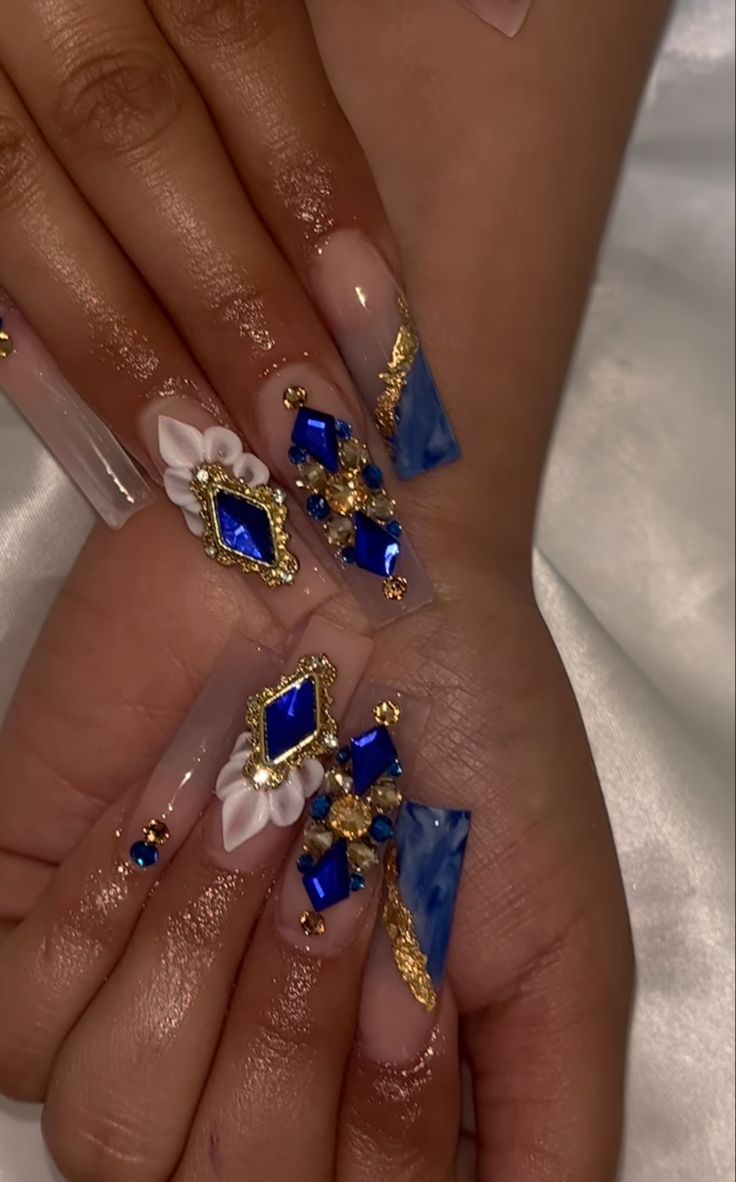 Sophisticated Nail Art: Intricate Designs with Nude and Blue Marbled Acrylics, Gold Accents, and Floral Embellishments.