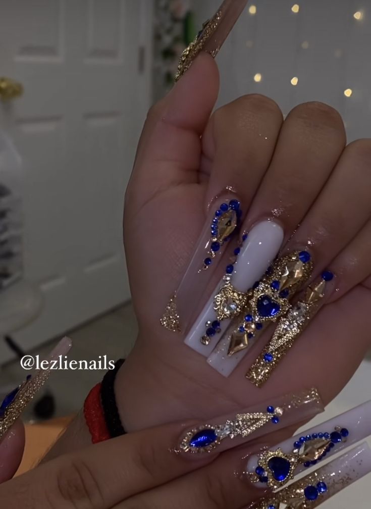 Elegant Stiletto Nail Design with Rhinestone Accents and Gold-Blue Luxury.